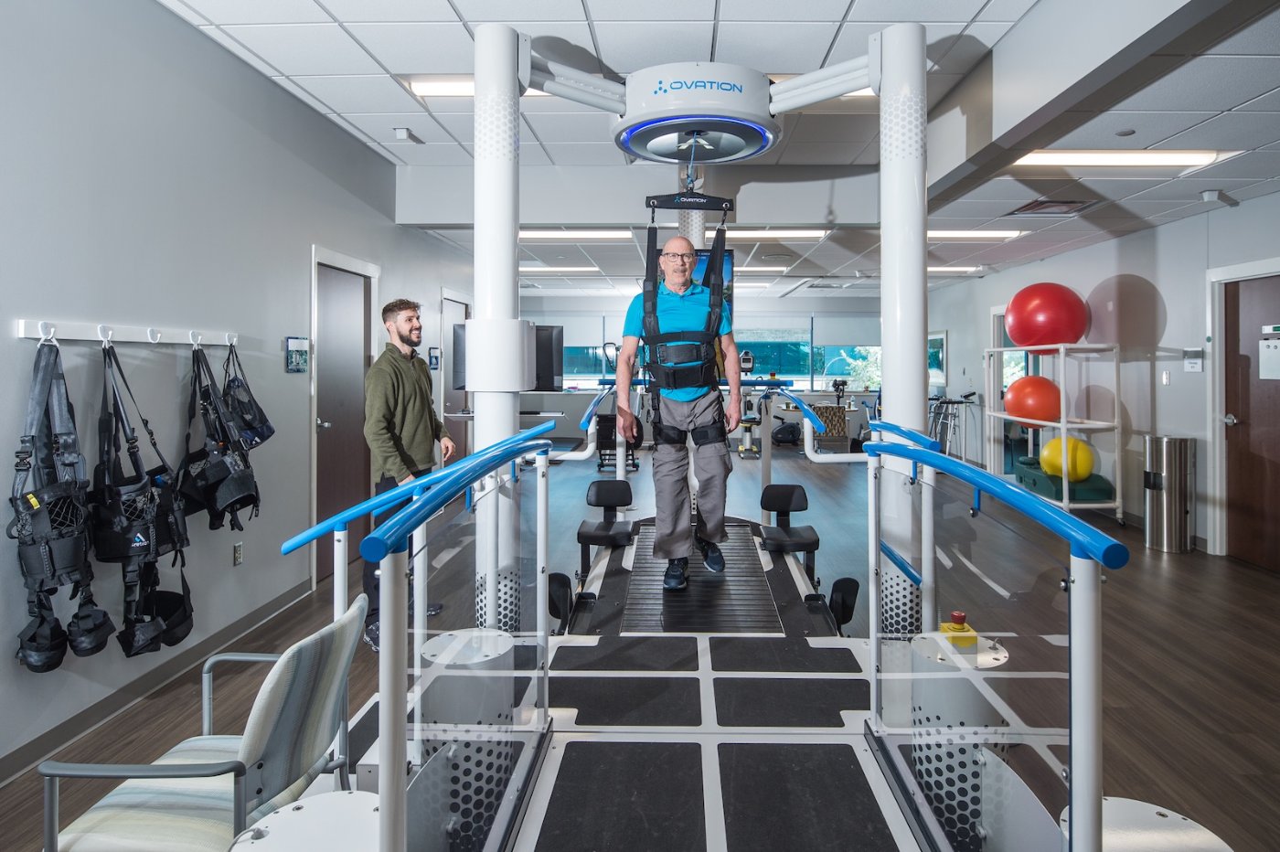 Patient walking on the Ovation treadmill between handrails with a therapist nearby