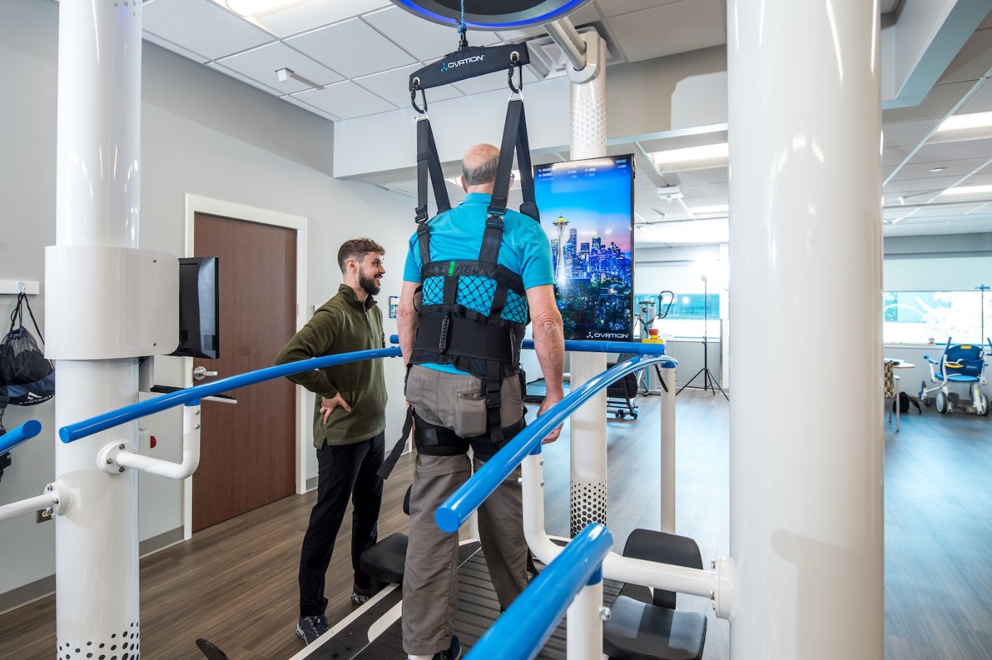 Clinician talking with a patient walking on Ovation in front of the Infotainment Display showing a city skyline