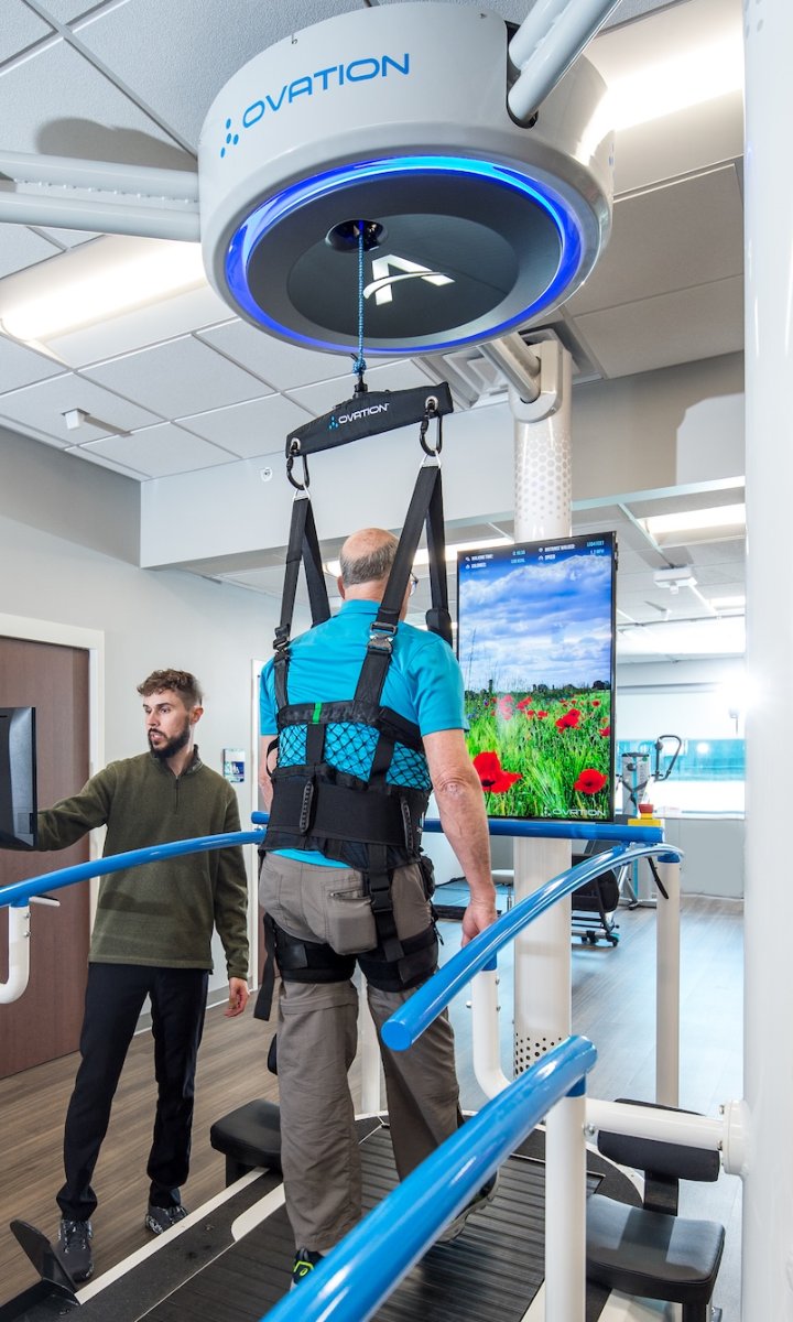 Patient walking toward the Ovation Infotainment Display showing a scenic walk and training metrics