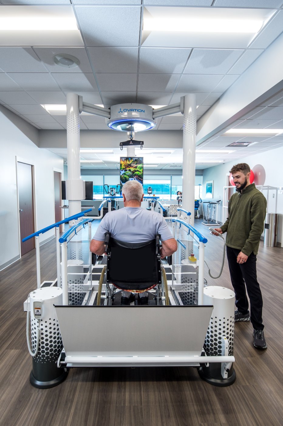 Patient in a wheelchair on the Ovation Launchpad platform while a therapist operates the lift