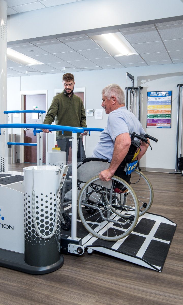 Patient in a wheelchair approaching the Ovation Launchpad ramp with a therapist