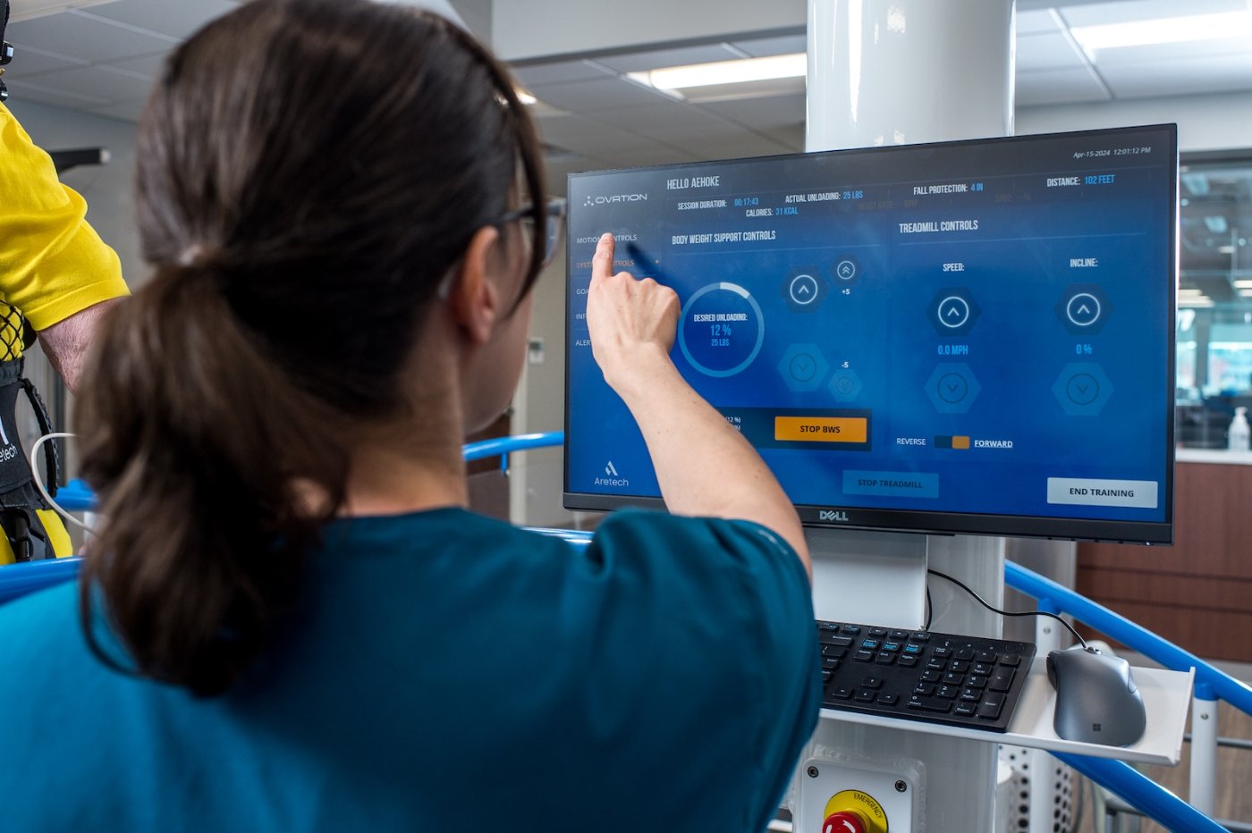 Therapist adjusting body-weight support and treadmill controls on the Ovation 24-inch touchscreen