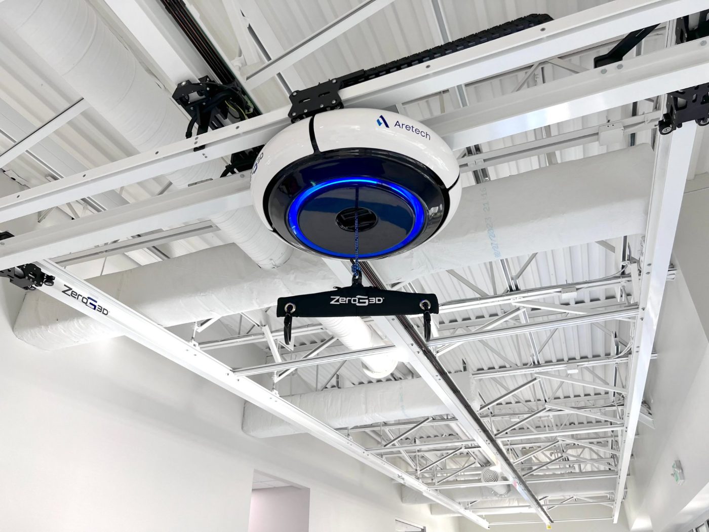 The ZeroG 3D robot — a white and blue disc — on its overhead track