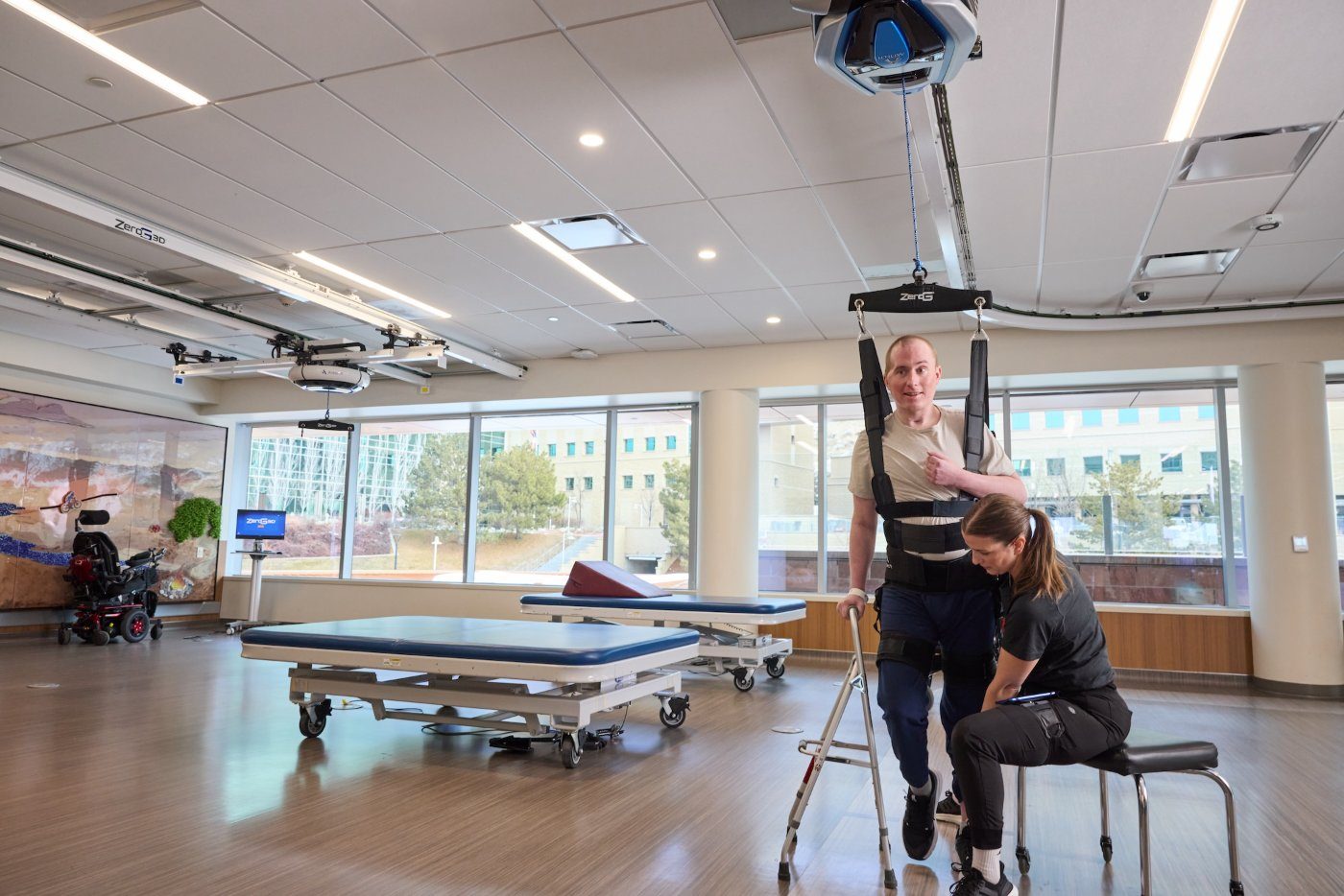 Patient taking first steps with a walker and constant ZeroG support beside a clinician