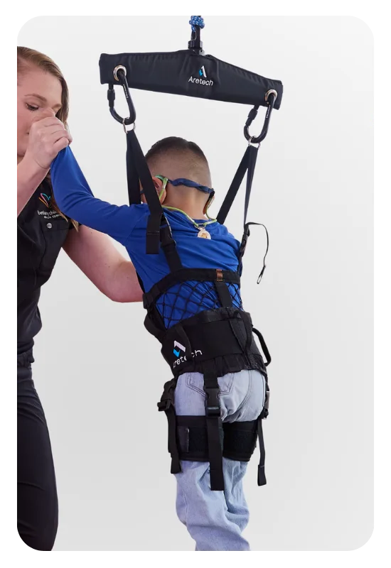 A clinician assisting a child supported in a ZeroG 3D pediatric harness