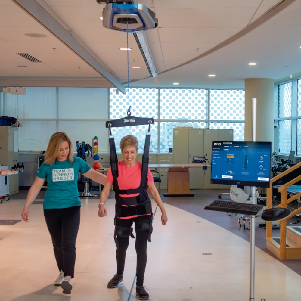 ZeroG therapy gym: patient walking with a therapist beneath the overhead ZeroG, touchscreen computer at right