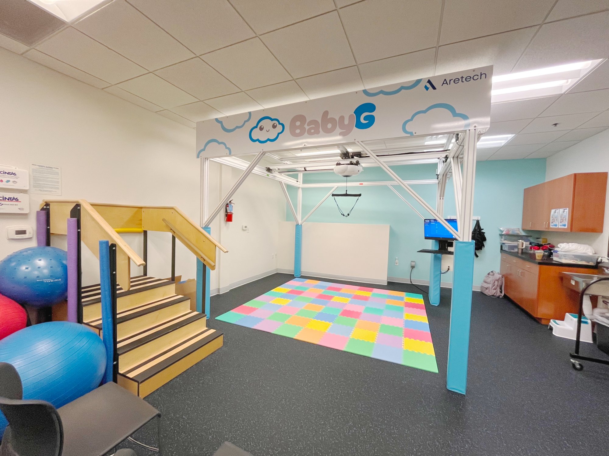 The BabyG overhead gantry and play mat in a pediatric therapy room